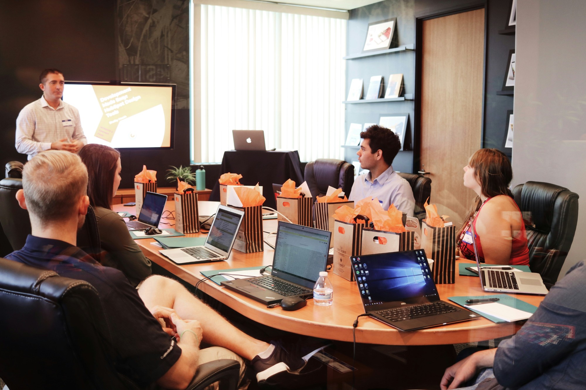 Team gathered around a conference table with laptops during a presentation